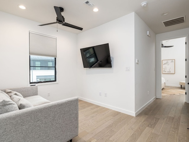 living room with light wood-style floors, baseboards, visible vents, and ceiling fan