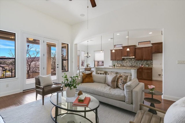 living area featuring recessed lighting, dark wood-style flooring, baseboards, and ceiling fan with notable chandelier