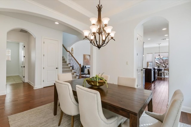 dining area with an inviting chandelier, visible vents, arched walkways, and dark wood-type flooring