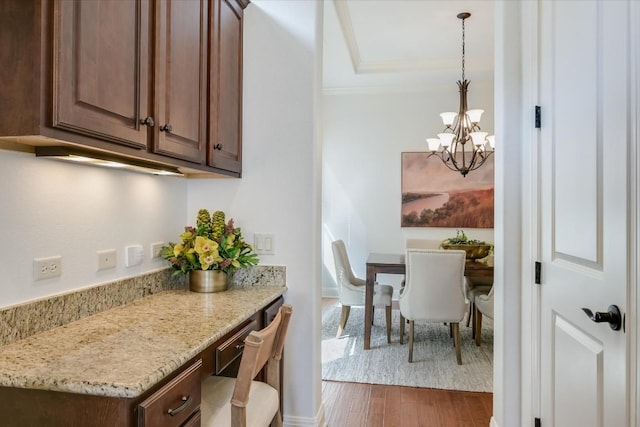 kitchen with light stone counters, dark wood finished floors, dark brown cabinetry, and hanging light fixtures