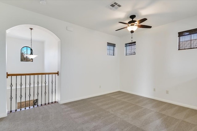 empty room featuring a ceiling fan, carpet flooring, visible vents, and baseboards