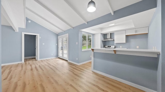 1112 Village Green Dr, Austin, TX 78753 - kitchen with wall chimney exhaust hood, white cabinetry, light wood finished floors, light countertops, and a kitchen breakfast bar