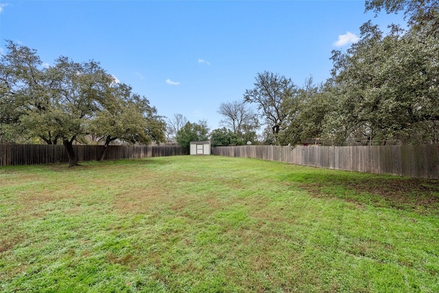 view of yard featuring a fenced backyard, a storage unit, and an outdoor structure