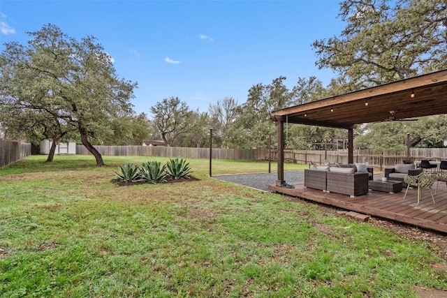 view of yard with an outbuilding, a fenced backyard, an outdoor living space, a wooden deck, and a storage unit