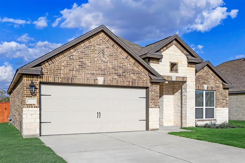 french country inspired facade featuring a garage, brick siding, a shingled roof, stone siding, and driveway