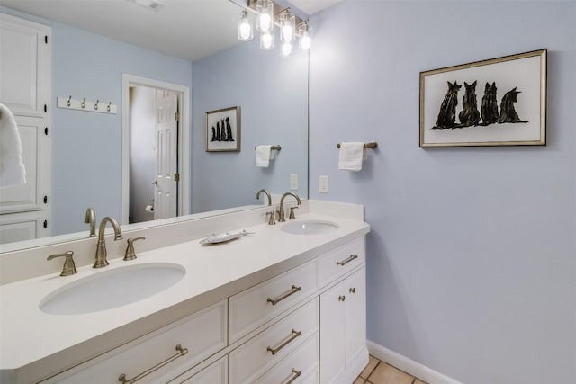 bathroom with double vanity, tile patterned flooring, a sink, and baseboards