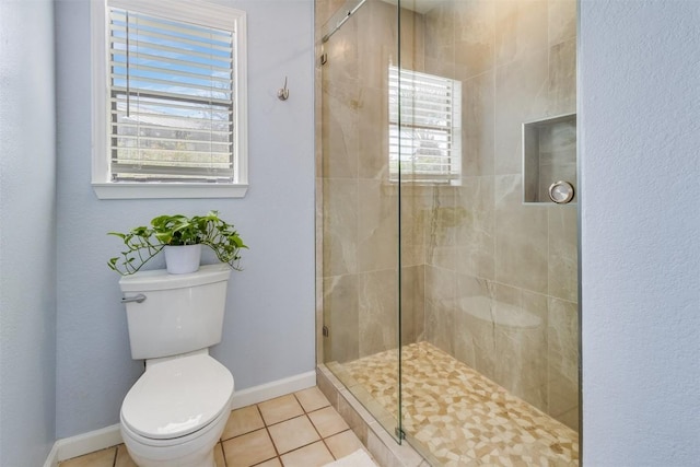 bathroom featuring tile patterned flooring, baseboards, a shower stall, and toilet