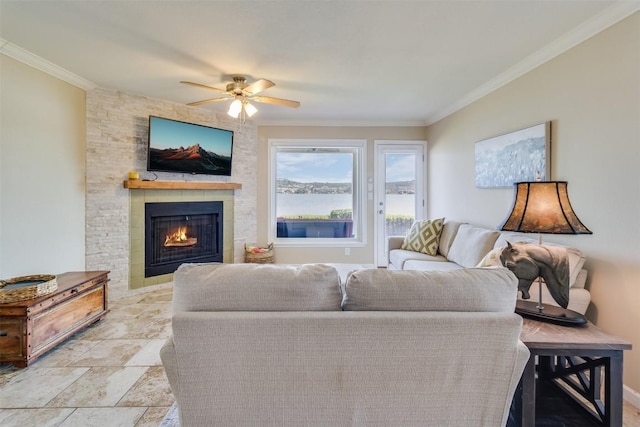 living room featuring stone finish floor, a large fireplace, ornamental molding, and a ceiling fan