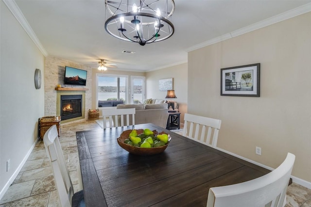 dining room featuring stone tile floors, visible vents, ornamental molding, a large fireplace, and baseboards