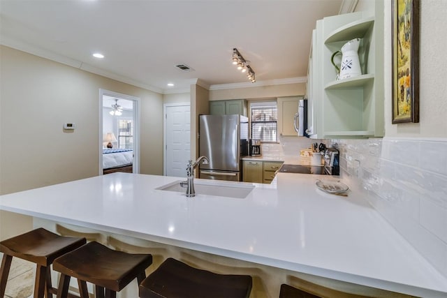 kitchen with visible vents, a peninsula, stainless steel appliances, light countertops, and a sink