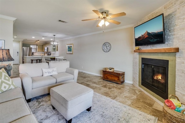 living area with baseboards, a stone fireplace, visible vents, and crown molding