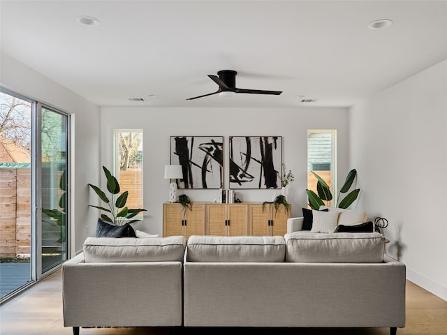 living room featuring light wood-style floors, visible vents, ceiling fan, and baseboards