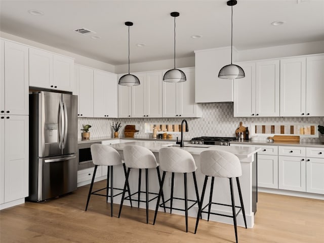 kitchen with light countertops, hanging light fixtures, stainless steel refrigerator with ice dispenser, and white cabinets