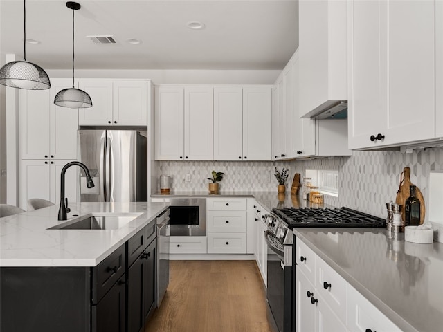 kitchen with visible vents, white cabinets, appliances with stainless steel finishes, hanging light fixtures, and a sink