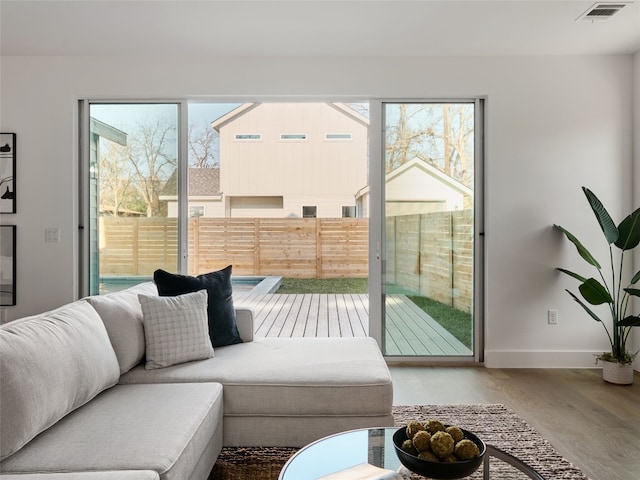 living room with wood finished floors, visible vents, and baseboards