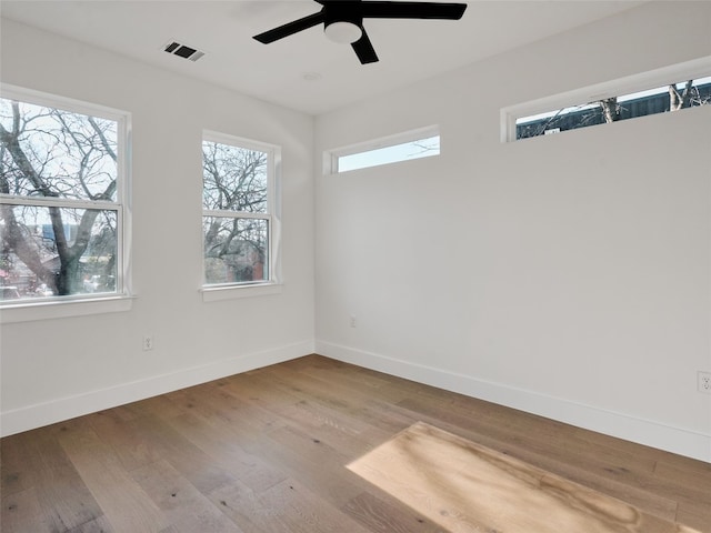 spare room with baseboards, visible vents, ceiling fan, and wood finished floors