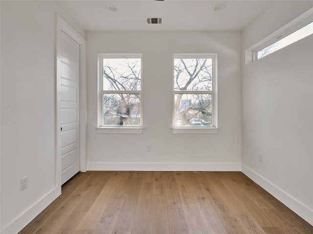 unfurnished room featuring light wood-style flooring, visible vents, and baseboards