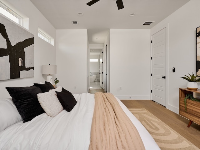 bedroom with ensuite bath, light wood-style flooring, visible vents, and baseboards