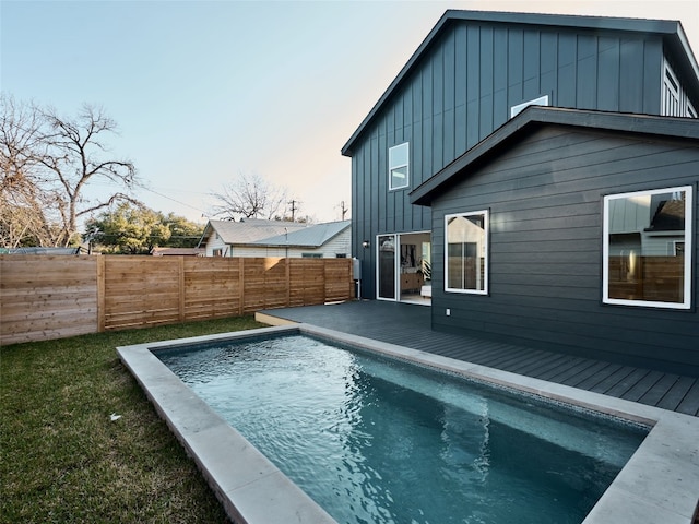 rear view of house featuring a wooden deck, a fenced in pool, board and batten siding, and a fenced backyard