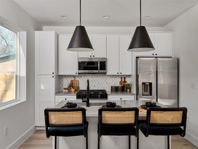1002 Gullett St Unit 2, Austin, TX 78702 - kitchen with appliances with stainless steel finishes, light wood-style flooring, decorative backsplash, hanging light fixtures, and recessed lighting