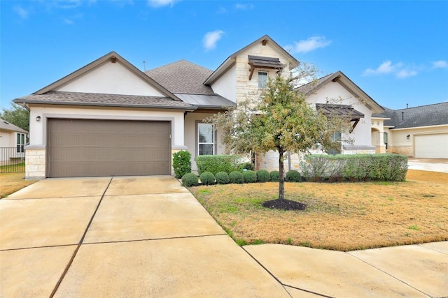 view of front of house featuring roof with shingles, stucco siding, a garage, stone siding, and driveway