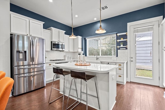 kitchen featuring a center island, pendant lighting, light countertops, appliances with stainless steel finishes, and white cabinetry