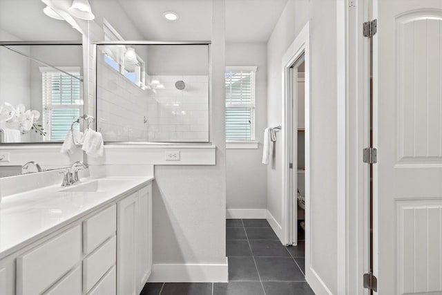 bathroom with tile patterned flooring, a healthy amount of sunlight, a shower stall, and vanity