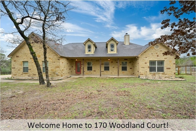 view of front of property with stone siding, a patio area, a chimney, and a front lawn