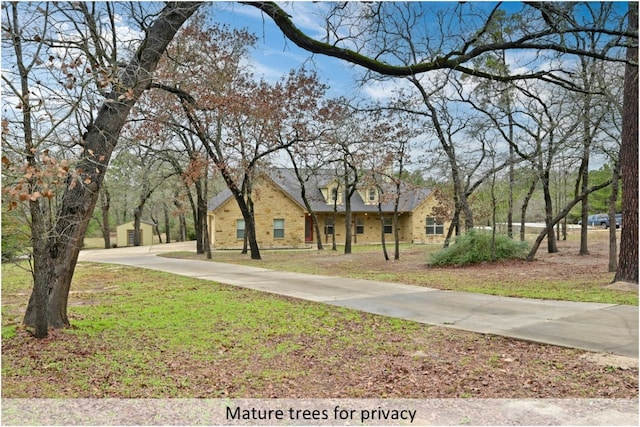 view of front facade featuring stone siding, concrete driveway, and a front yard