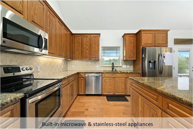 kitchen featuring plenty of natural light, a sink, light wood finished floors, and stainless steel appliances
