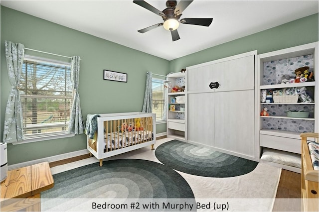 bedroom with a nursery area, baseboards, and multiple windows