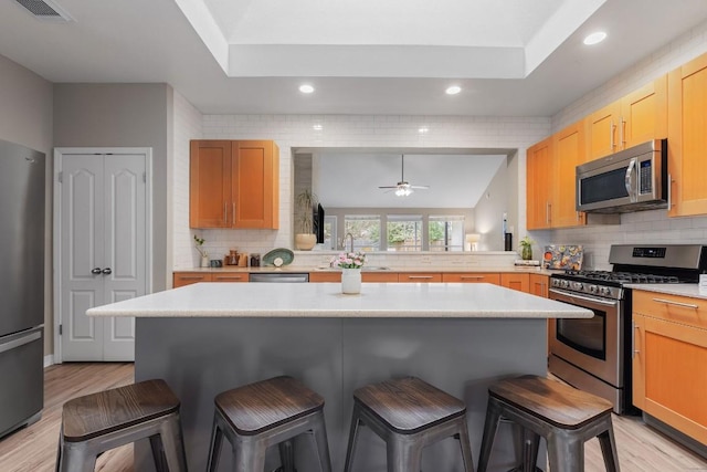 kitchen with a breakfast bar area, stainless steel appliances, a sink, visible vents, and light countertops