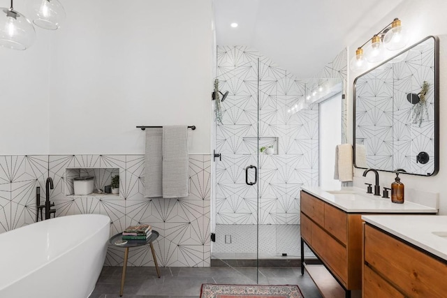 full bath with a stall shower, tile patterned floors, a freestanding bath, vanity, and tile walls