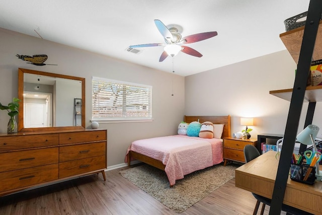 bedroom featuring light wood-style floors, visible vents, baseboards, and a ceiling fan