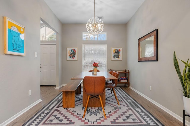 dining space featuring a chandelier, wood finished floors, and baseboards