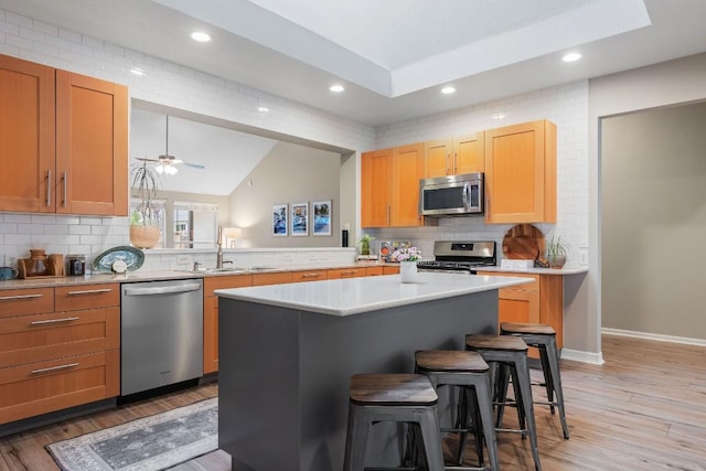 kitchen featuring a kitchen island, a kitchen breakfast bar, stainless steel appliances, light countertops, and light wood-style floors