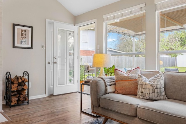 living room with light wood-style floors, lofted ceiling, and baseboards