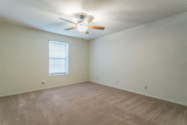 empty room featuring light carpet, ceiling fan, a textured ceiling, and baseboards