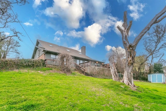 back of house featuring an outbuilding, a storage shed, stairway, a lawn, and a chimney