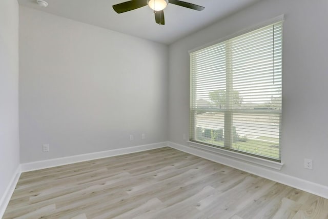 spare room featuring light wood finished floors, baseboards, and a ceiling fan