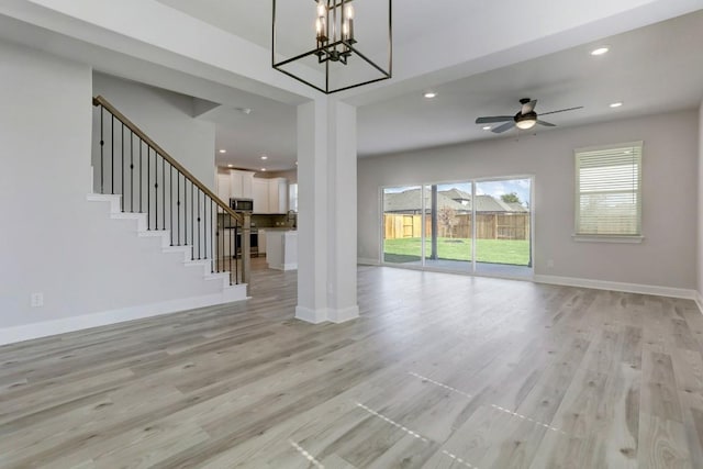 unfurnished living room with baseboards, stairway, and light wood finished floors