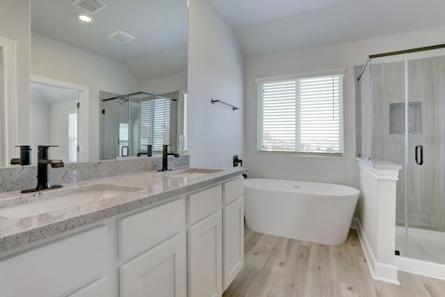 bathroom featuring double vanity, visible vents, a sink, and wood finished floors