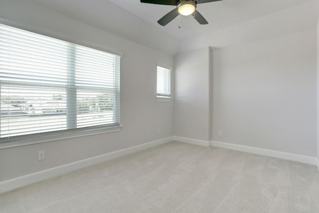 spare room with baseboards, lofted ceiling, a ceiling fan, and light colored carpet