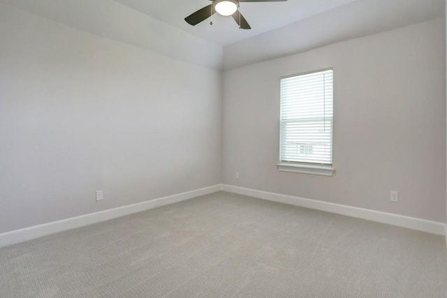 spare room with baseboards, vaulted ceiling, a ceiling fan, and light colored carpet