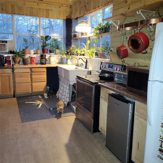 interior space with refrigerator, stainless steel electric range oven, a wealth of natural light, and freestanding refrigerator