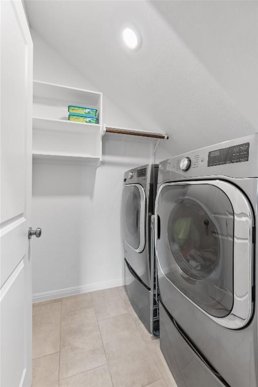 washroom featuring laundry area, light tile patterned floors, and washer and clothes dryer