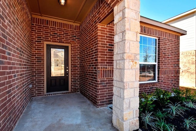 entrance to property featuring brick siding and a patio