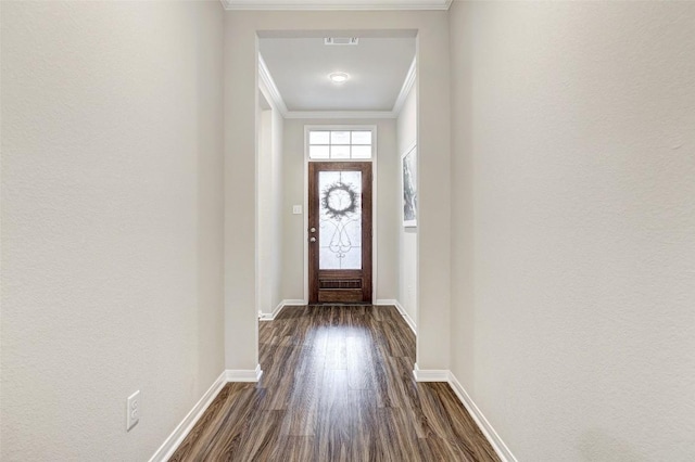 doorway with baseboards, visible vents, dark wood-type flooring, and ornamental molding