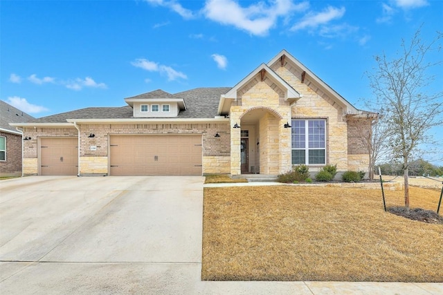 view of front facade with driveway, a shingled roof, stone siding, an attached garage, and a front yard