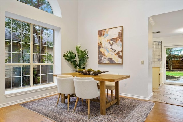 dining room featuring crown molding, visible vents, baseboards, and wood finished floors